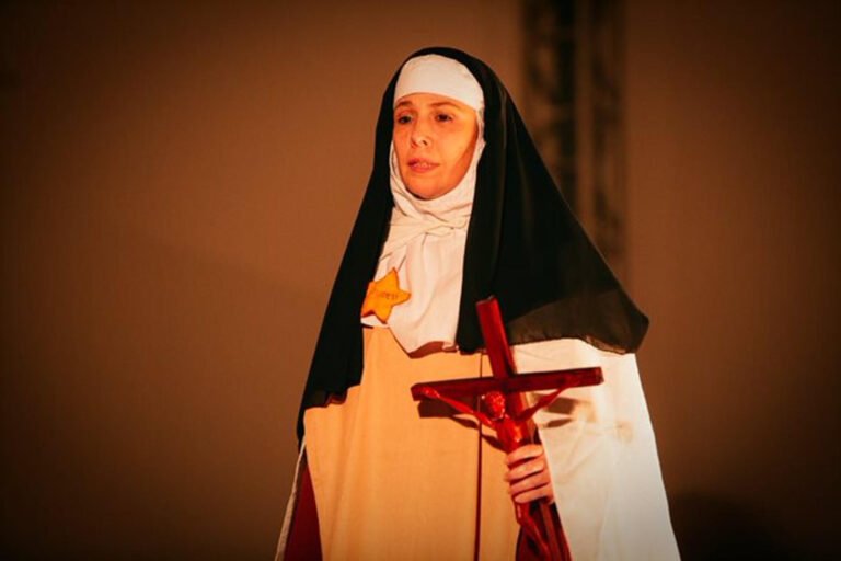 Daniela Schitini em cena de Edith Stein, a Estrela e a Cruz, segurando um crucifixo