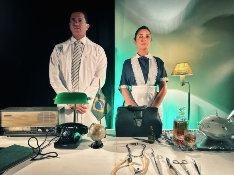 Pedro Osório e Maíra Chasseraux em cena de Dr. Carrasco e sua criada Matti, divididos entre consultório e cozinha